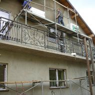 Widok na balustradę balkonową, w tle prace przy budowie domu