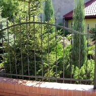 Proste eleganckie ogrodzenie kute - w tle dom z ogrodem